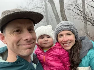 Dan Ennis, wife and daughter smiling for camera on winter hike in Brevard area.