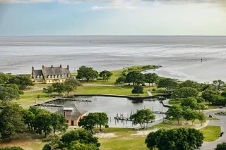 Aerial of Whalehead Club and grounds with ocean in background during daytime.