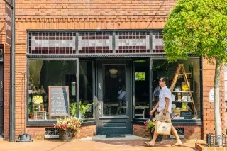 Man with shopping back walking in front of art gallery in Halifax on beautiful sunny day.