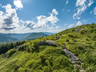 Aerial of woman on hiking trail at Black Balsam Knob with mountains in background.