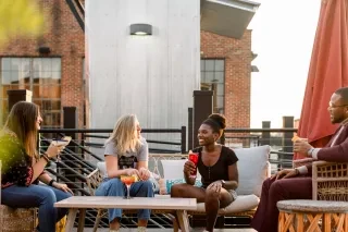 Four friends enjoying drinks on rooftop in Hickory during daytime.