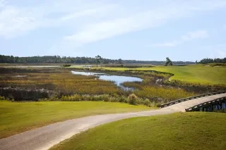 Beach access heading down to beach where person is seated on beach chair.