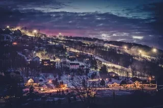 Long-range view of ski slopes and community at night, lit up under dark blue sky.