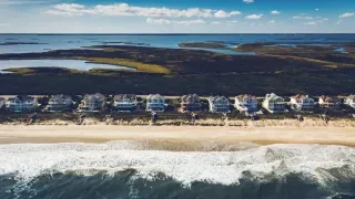Aerial of vacation rentals on beach with sound in background.