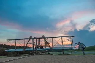 Plane replica outside at Wright Brothers National Memorial during sunset.