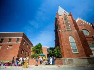 Exterior of brick cultural building with people mingling outside