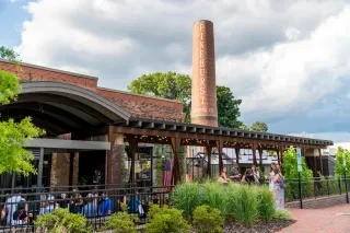 Exterior of brewery with industrial feel and people standing outside