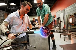 Craftsman working on glass art in workshop.