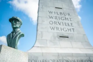 Bust of a Wright Brother in front of national monument at Wright Brothers Memorial.
