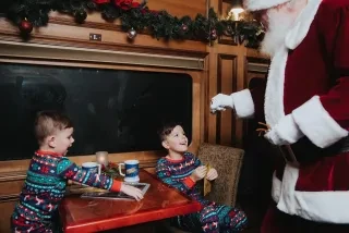 Santa giving two children a bell on Polar Express train ride.