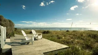 Adirondack chairs sitting on wooden platform overlooking marshy terrain and ocean on Bald Head Island.