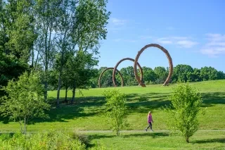 Woman walking on path in the outdoor Museum Park at North Carolina Museum of Art on sunny day